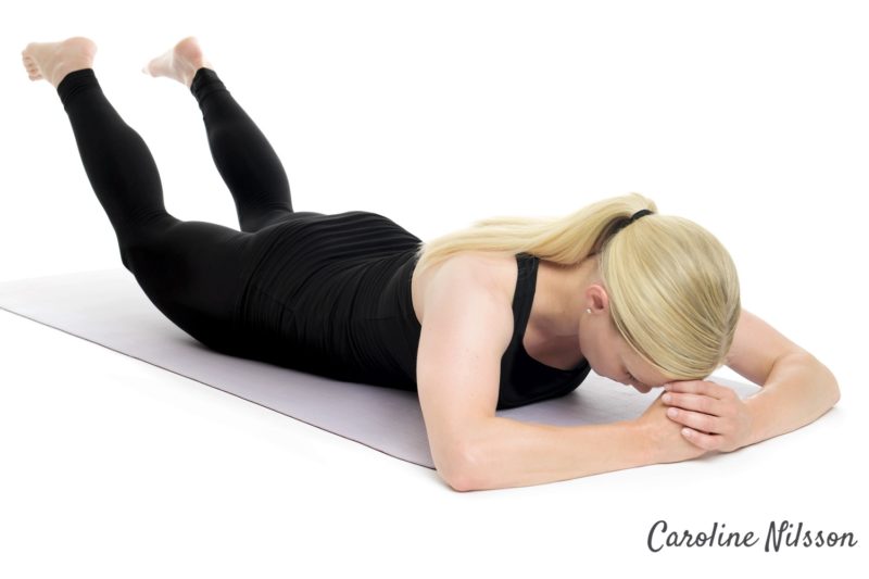 Ligg på mage och lygt benen för att träna ryggens muskler